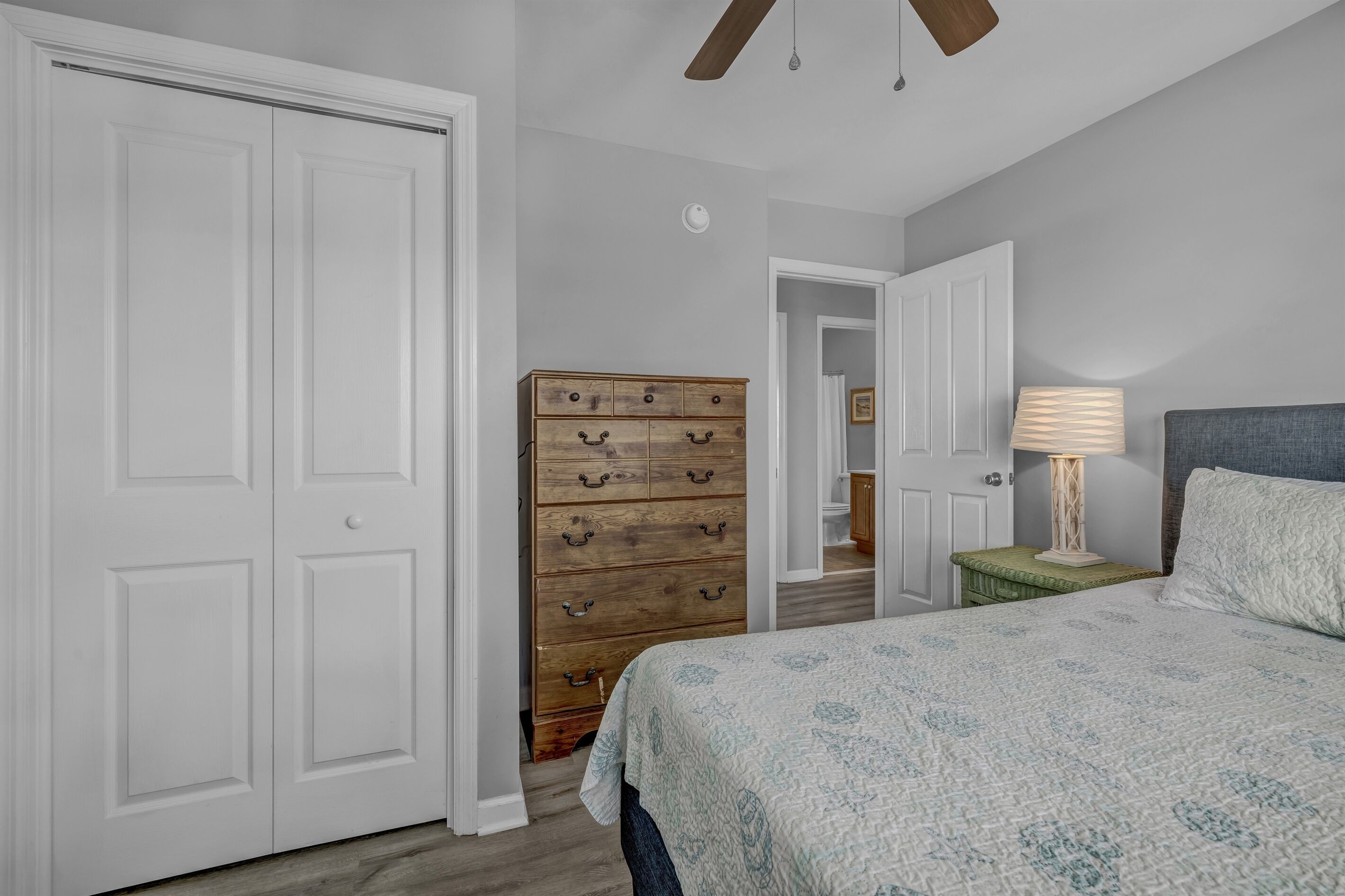 A bedroom with a bed, dresser, and a ceiling fan.