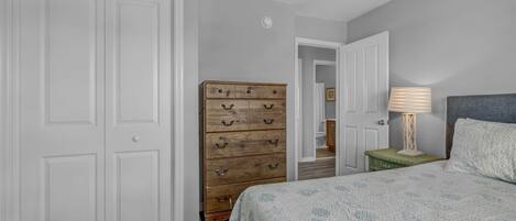 A bedroom with a bed, dresser, and a ceiling fan.