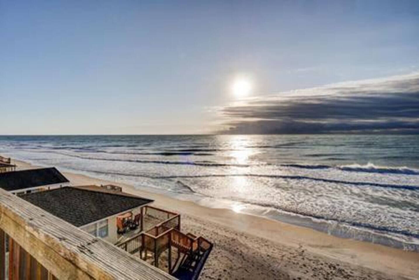 A beach view with a wooden deck and a glass-enclosed area.