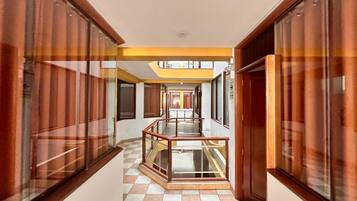 A corridor with a glass railing, checkered floor, and wooden paneling on the walls.