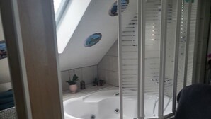 Ein Badezimmer im Eckbereich mit Badewanne, Duschkabine und Dachfenster.