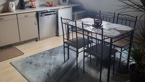 Eine kompakte Küche mit Oberlicht, ein Essbereich mit Tisch und Stühlen sowie ein Blumentopf.