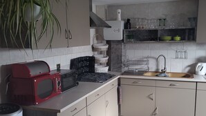 Eine moderne Küche mit Mikrowelle, Toaster und einem roten Grill. Es gibt ein Spülbecken mit Wasserhahn, eine Arbeitsplatte mit einer Pflanze und einen Holzboden.