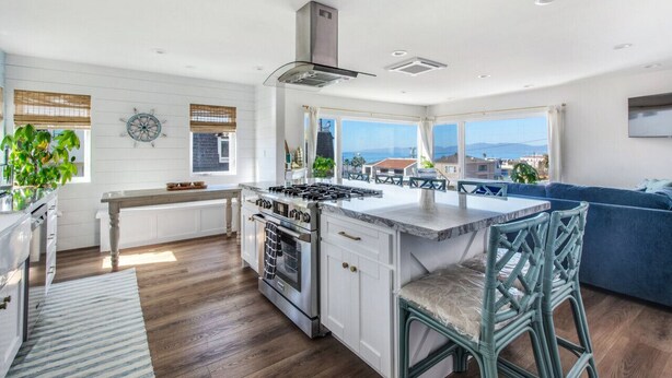 Una cocina moderna con una isla central, ventanas amplias y vista al mar.