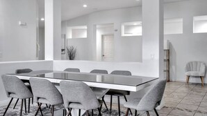Un espace repas moderne avec une table à plateau en verre et des chaises à revêtement gris.