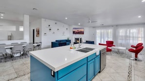 Une cuisine moderne avec un îlot central, des meubles bleus et des chaises rouges.
