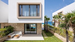 A modern two-story house with a stone facade, a glass door entrance, a patio with outdoor furniture, and a view of the sea. - Awesome home in Tkon-Ugrinic (Tkon-Ugrinic)