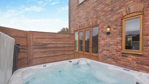A hot tub in a backyard with a brick wall and wooden fence. - Lake View 2 - UK45578 (Louth)