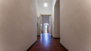 Un pasillo con piso de baldosas, un ventilador de techo y una puerta que da a otra habitación.