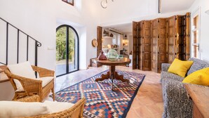Amplia sala de estar con muebles de mimbre, un tapete estampado y armarios de madera.