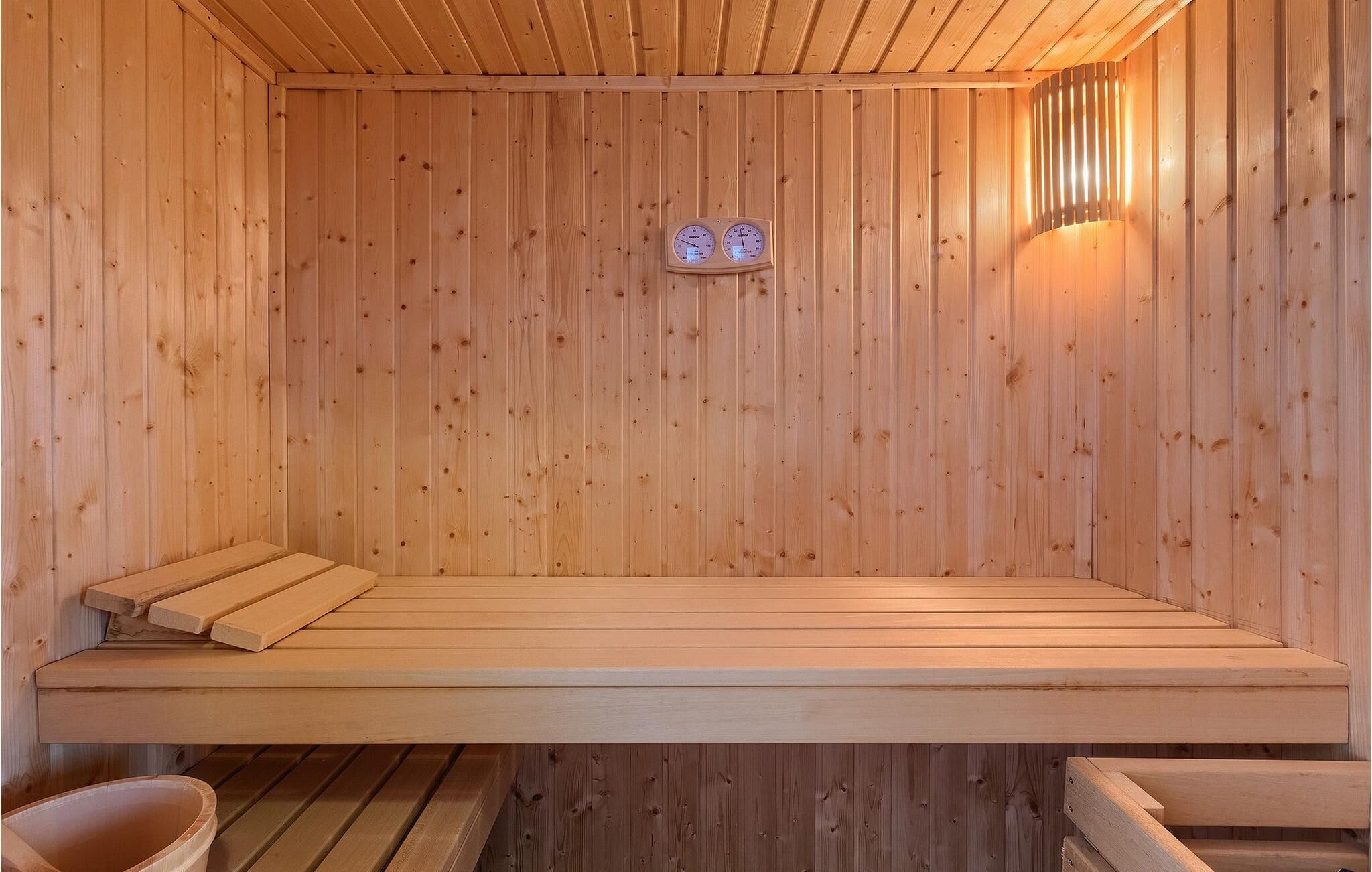 Eine Holzsauna mit Bänken und einem an der Wand befestigten Thermometer.
