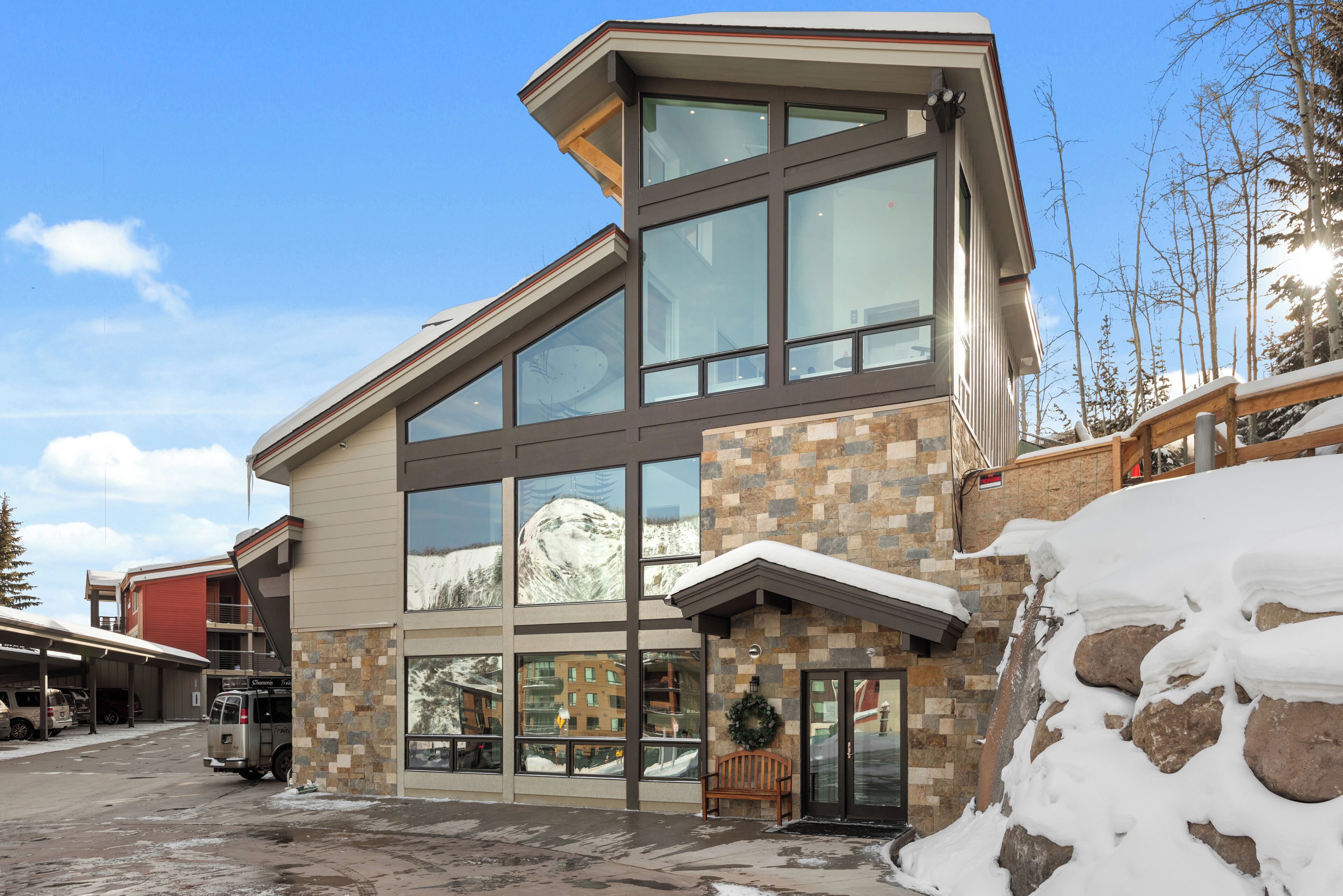 Un edificio moderno con grandes ventanales, fachada de piedra y techo cubierto de nieve.