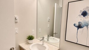 A modern bathroom with a toilet, a sink, a mirror, and a potted plant. - Perfect Brand New Suite In The Heart of Sidney (Sidney)