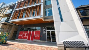 A modern building with a glass facade, a prominent vertical white structure, and a brick-paved entrance. - Perfect Brand New Suite In The Heart of Sidney (Sidney)