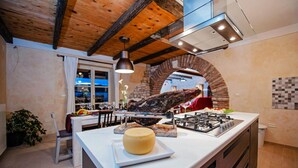 A modern kitchen with a central island, a hanging meat display, and a stone archway. - Stunning home in Bale (Bale)