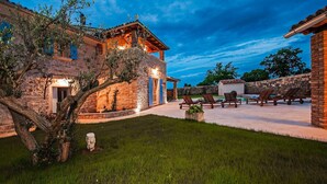 A stone building with a patio area, outdoor seating, and a well-maintained lawn. - Stunning home in Bale (Bale)