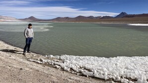 A person standing by a lake with mountains in the background. - Terra Luna Lodge Atacama (San Pedro de Atacama)