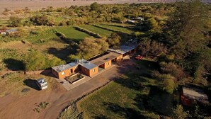 An aerial view of a rural property with terraced fields, a few buildings, and a clear view of distant mountains. - Terra Luna Lodge Atacama (San Pedro de Atacama)