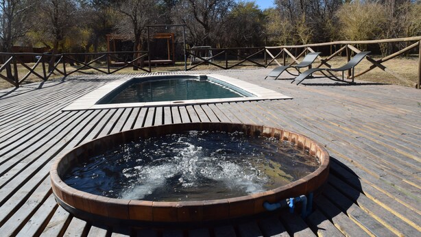 A hot tub on a wooden deck with a pool in the background. - Terra Luna Lodge Atacama (San Pedro de Atacama)