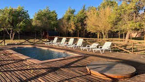 A wooden deck with a pool, lounge chairs, and a hot tub. - Terra Luna Lodge Atacama (San Pedro de Atacama)