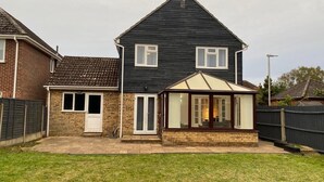 A two-story house with a dark exterior, a front porch with glass doors, and a brick driveway. - Spacious 4 bedroom house close to all the main activities in Colchester (Colchester)