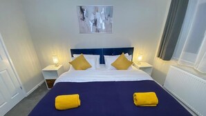 A hotel room with a large bed, two bedside lamps, a headboard, and a painting on the wall. - Spacious 4 bedroom house close to all the main activities in Colchester (Colchester)