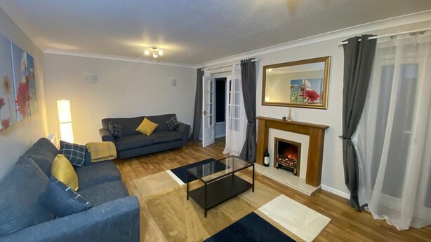 A living room with a sofa, coffee table, fireplace, and curtains. - Spacious 4 bedroom house close to all the main activities in Colchester (Colchester)