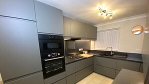 A modern kitchen with grey cabinets, a built-in oven, and a stainless steel countertop. - Spacious 4 bedroom house close to all the main activities in Colchester (Colchester)