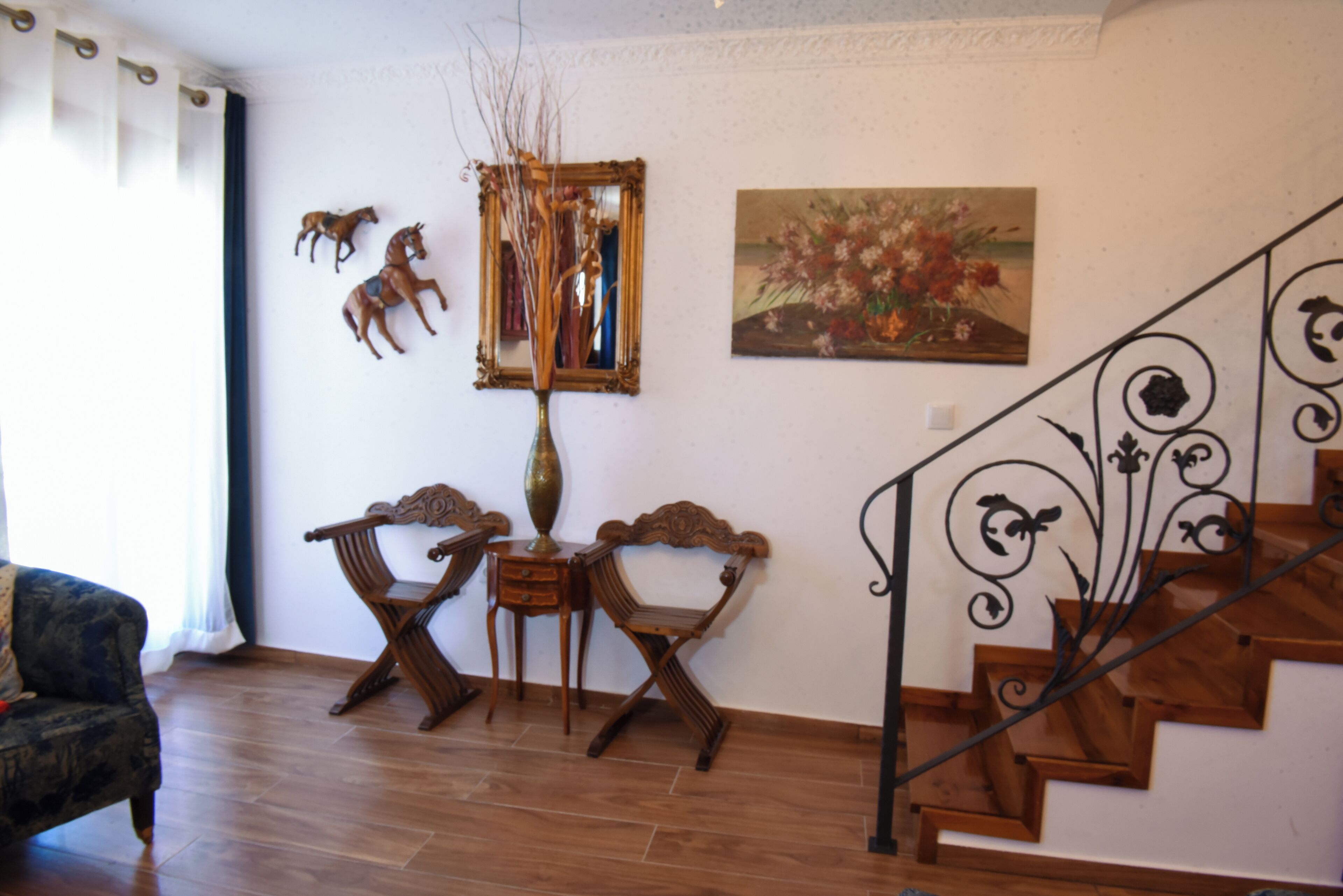 A room with a wooden staircase, a sofa, and a painting on the wall.