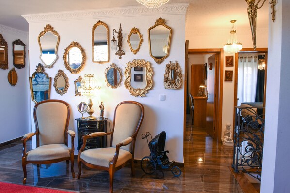A room with two wooden chairs, a small table with a lamp, and a collection of mirrors on the wall. - PH in Alto Douro Vinhateiro (Torre de Moncorvo)