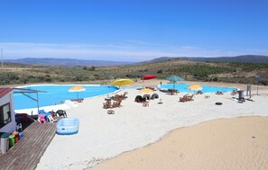 A beach with multiple swimming pools, lounge chairs, and umbrellas. - PH in Alto Douro Vinhateiro (Torre de Moncorvo)