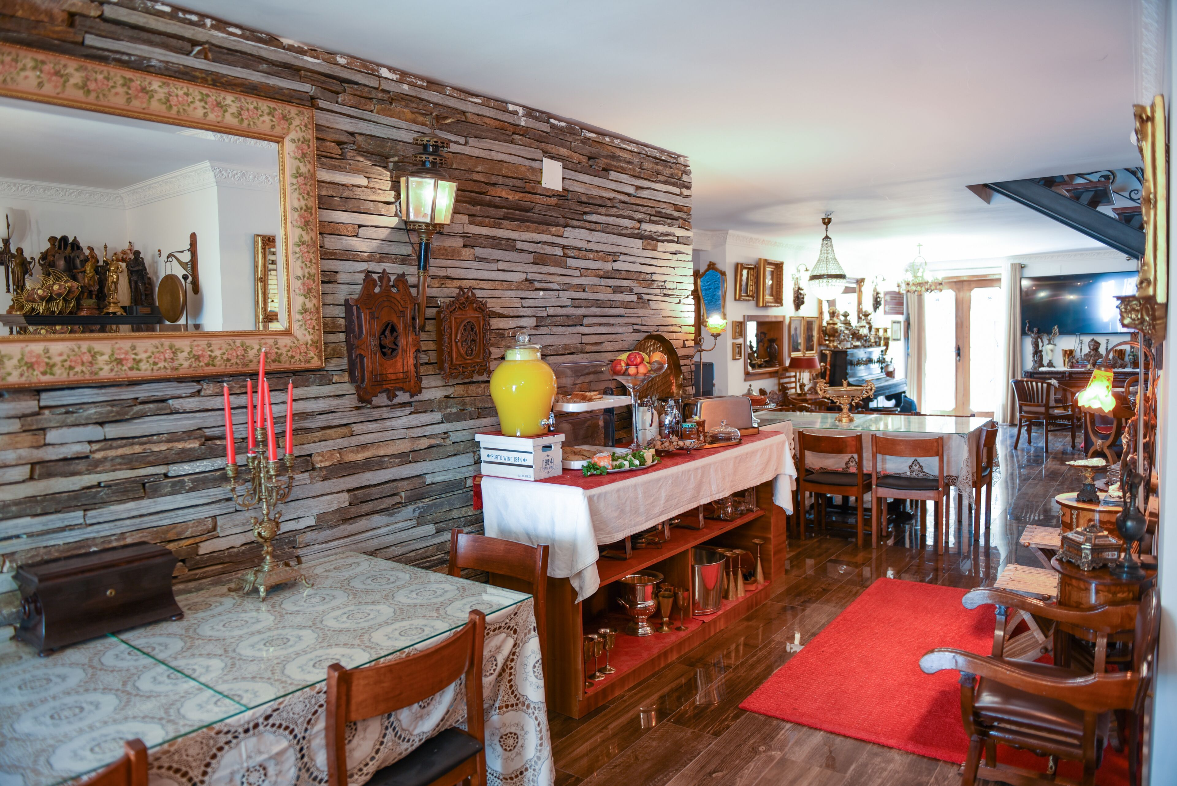 Un comedor con pared de piedra, mobiliario de madera y alfombra roja.