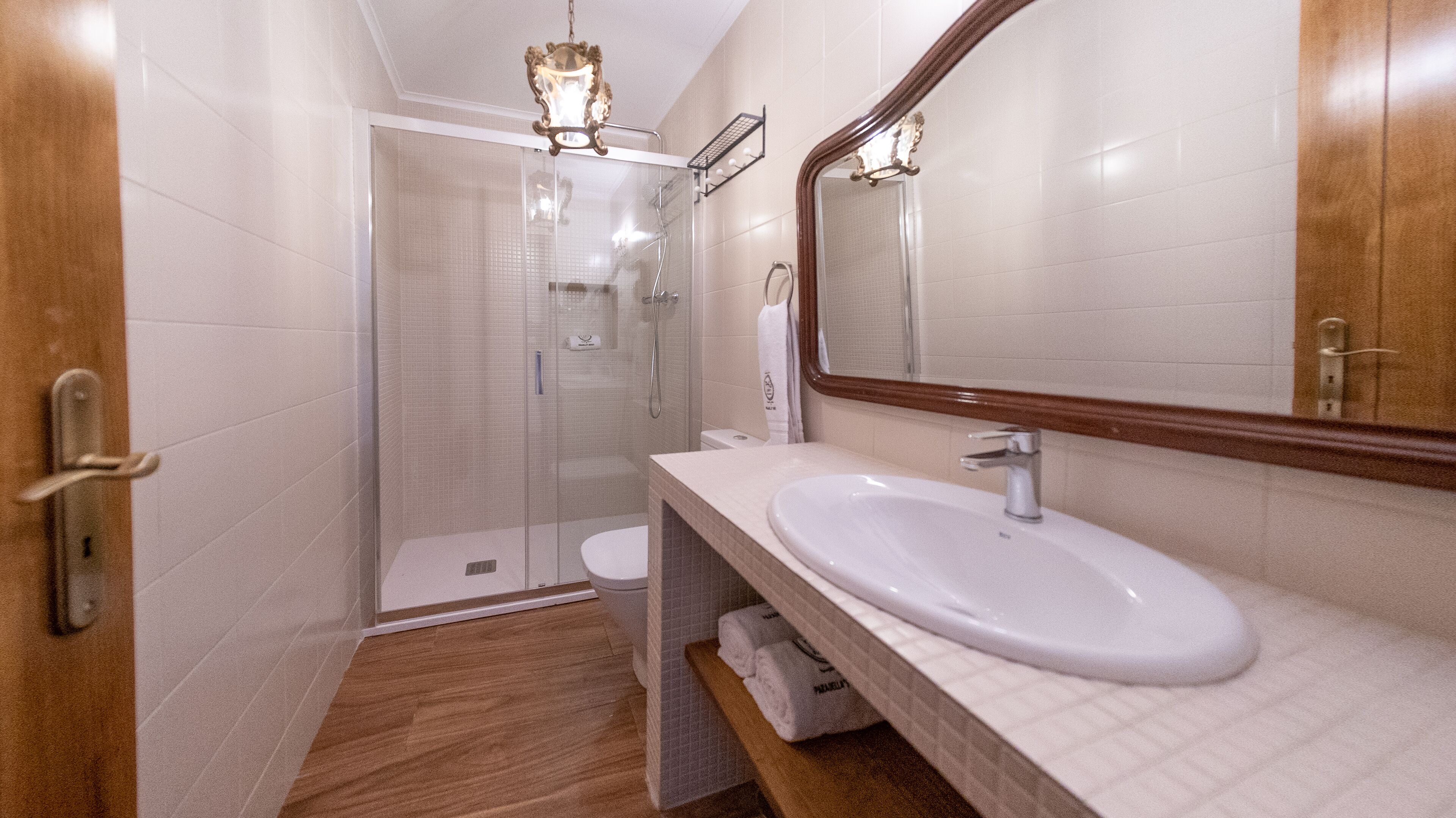 A modern bathroom with a glass-enclosed shower, a white sink, and a large mirror.
