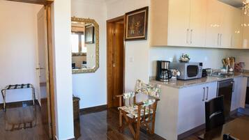 Cocina compacta con microondas, tostadora y lavabo. Se ve una silla de madera y una mesa pequeña.