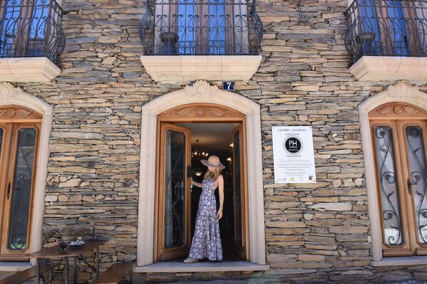 A stone building with a number 7 sign above the entrance, a signboard for Casa de Casa Museo, and a woman in a dress standing at the doorway. - PH in Alto Douro Vinhateiro (Torre de Moncorvo)