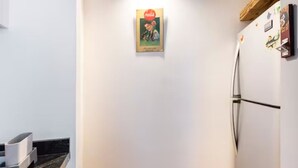 Une cuisine équipée d’un réfrigérateur, d’un four à micro-ondes et d’une machine à café, le tout posé sur le plan de travail.