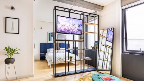 Une chambre moderne avec une grande télévision, un lit, un bureau et une fenêtre.