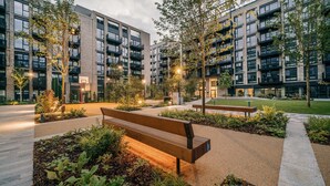A modern apartment building with multiple balconies, a basketball court, and a well-maintained garden area with benches. - City Apartments by Dublin At Home (Dublin)