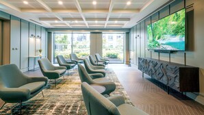 A modern waiting area with a row of chairs, a large TV screen, and a view of greenery outside. - City Apartments by Dublin At Home (Dublin)