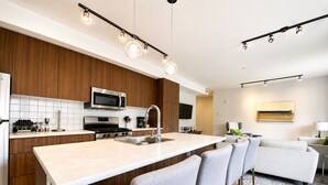 Eine moderne Küche mit einer zentralen Kochinsel, Edelstahlgeräten und einem Essbereich mit einer Couch und Stühlen.
