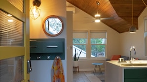 A kitchen with a wooden ceiling, a round mirror, and a window with a view of trees. - Gorgeous, one-bedroom garage apartment in a quiet neighborhood (Austin)