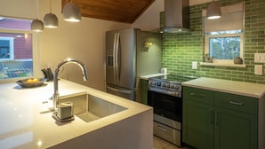 A modern kitchen with a stainless steel refrigerator, a built-in oven, and a green tiled backsplash. - Gorgeous, one-bedroom garage apartment in a quiet neighborhood (Austin)