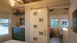 A bedroom with a bed, a dresser, a closet, and a sliding door leading to a kitchen area. - Gorgeous, one-bedroom garage apartment in a quiet neighborhood (Austin)