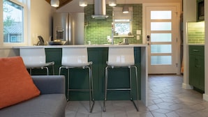A modern kitchen with a wooden ceiling, green bar stools, and a built-in oven. - Gorgeous, one-bedroom garage apartment in a quiet neighborhood (Austin)