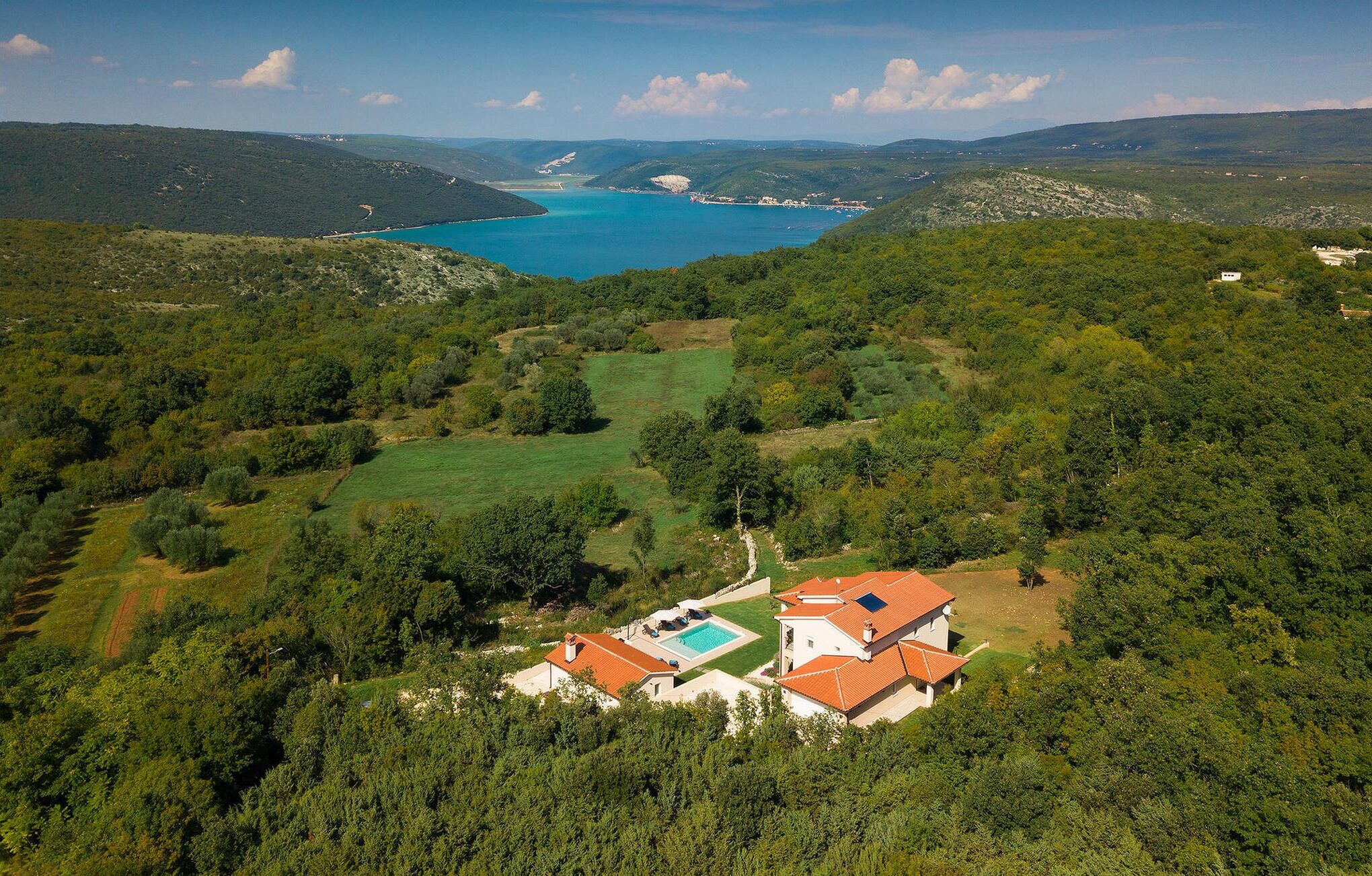 A villa with a swimming pool, surrounded by lush greenery and hills.