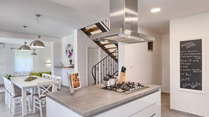 A modern kitchen with a central island, stainless steel appliances, and a chalkboard with a recipe.
