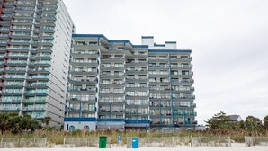 A multi-story hotel with balconies, located near a sandy beach. - ⛱ FABULOUS DIRECT OCEANFRONT KING BED⛱ ALL NEW RENOVATION! BALCONY! POOL VIEW ! (Myrtle Beach)