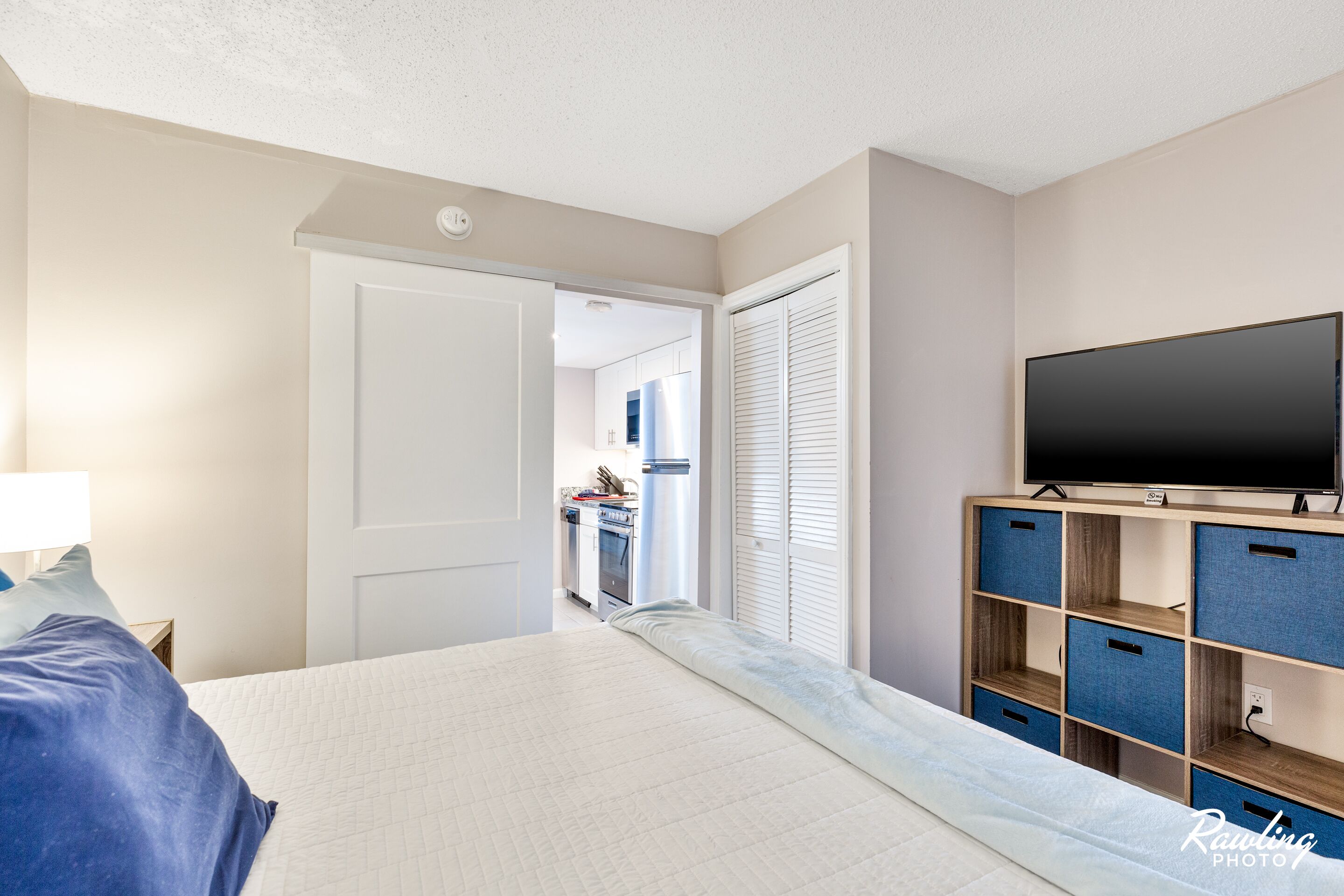 A bedroom with a bed, a television, and a storage unit.