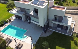 A modern two-story house with a swimming pool, outdoor seating, and solar panels. - Stunning home in Krnica (Krnica)