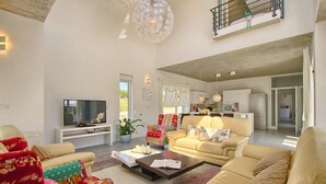 A spacious living room with a flat-screen TV, a sofa set, a coffee table, and a dining area with a kitchen in the background. - Stunning home in Krnica (Krnica)